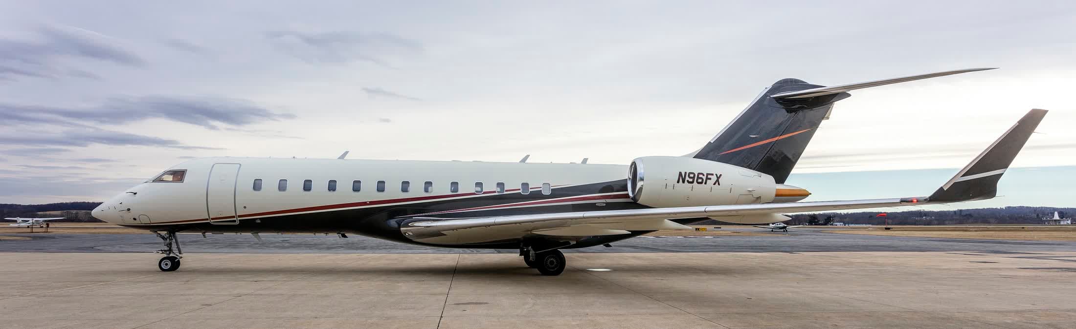 A private jet parked on an empty apron under a grey sky