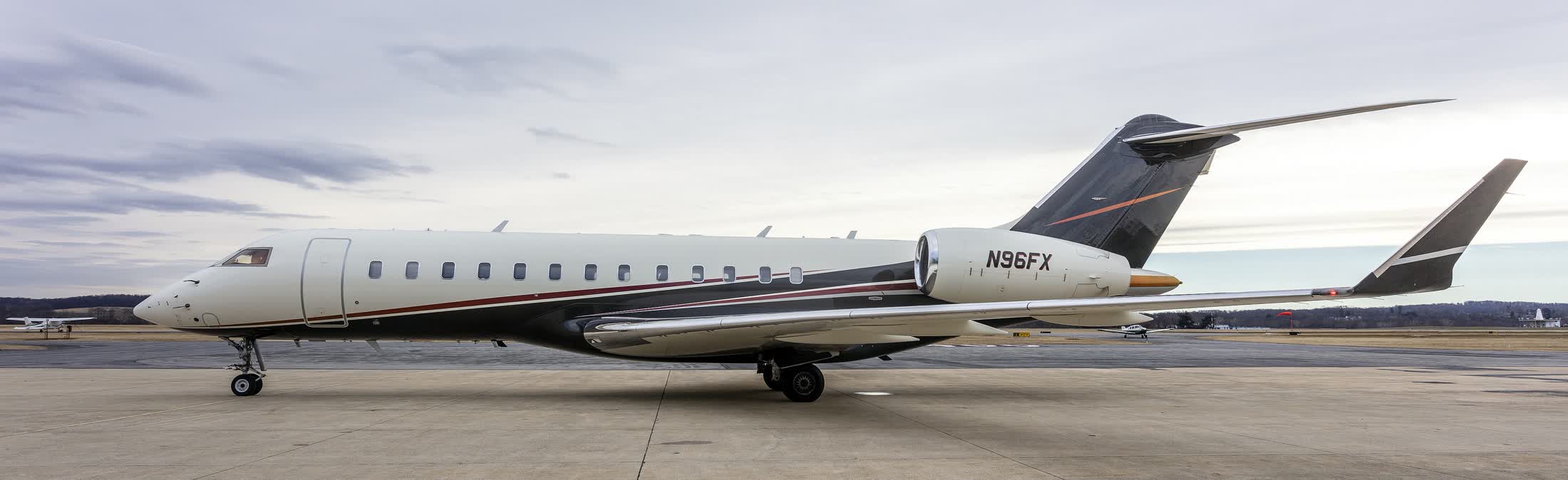 A private jet parked on an empty apron under a grey sky
